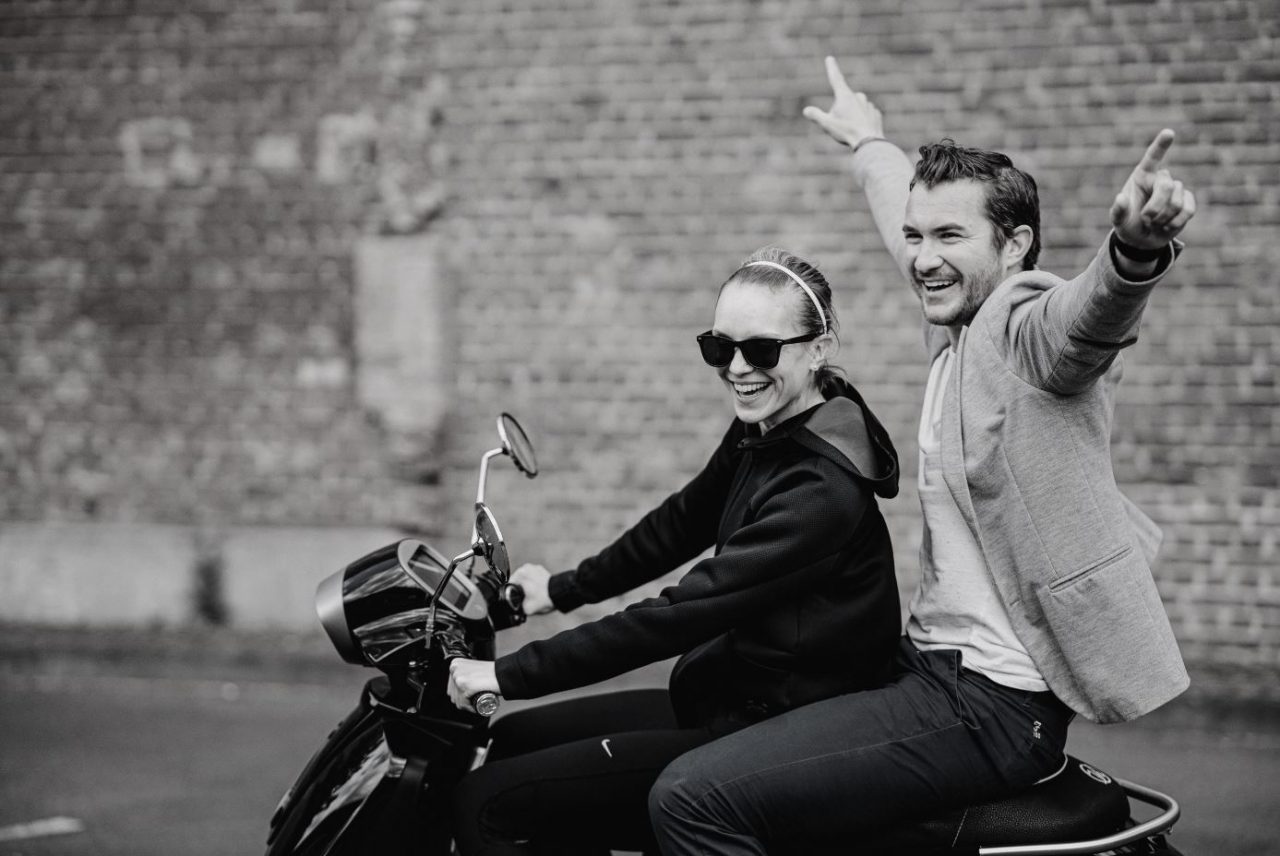 zwei Menschen die auf dem elektronischen Roller Modell 54 iconic von Kumpan fahren